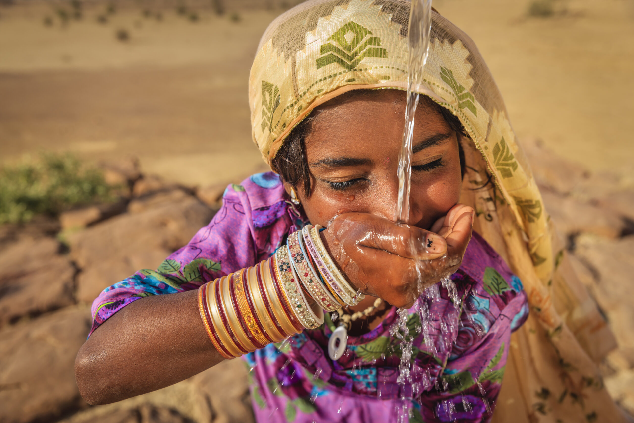 Indian little girl is drinking fresh water, desert village, Thar Desert, Rajasthan, India. Potable water is very precious on the desert - Rajasthani women and children often walk long distances through the desert to bring back jugs of water that they carry on their heads.